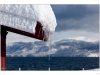 Detail on the snow accumulation left by a powerful winter storm in the lake tahoe area. The foreground is the snow accumulation on a roof and the background is the lake Tahoe.