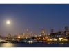 A panorama of San Francisco with the Coit tower and the Transamerica tower at night with the full moon.